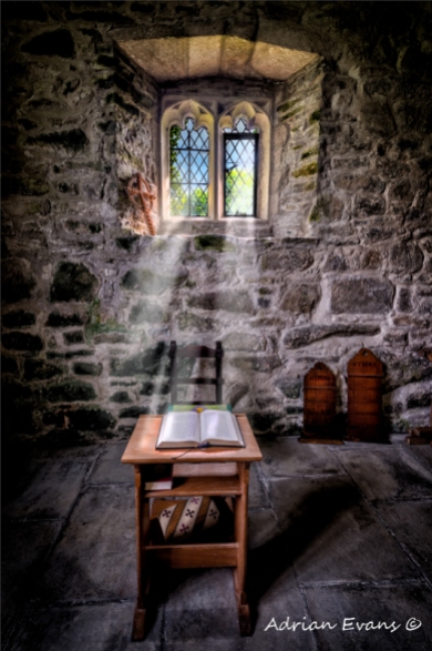 sunlight through the ancient chapel window illuminating the old Bible and Celtic cross